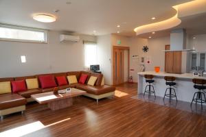 Una sala de estar con un sofá y una mesa y una cocina. en Hakodate MOTOMACHI guesthouse, en Hakodate