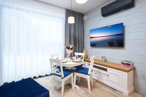 a dining room with a table and a tv on a wall at Apartament Olimpijska z ogródkiem i widokiem na jezioro in Olsztyn