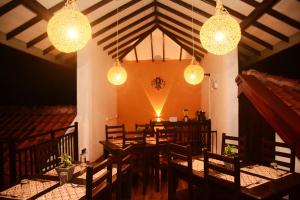 a dining room with wooden tables and lights at Ayubowan Homestay Katunayake in Katunayaka