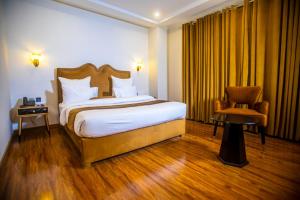 um quarto de hotel com uma cama e uma cadeira em The Rich Hotel & Apartments em Lahore