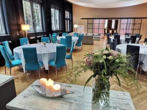 Ośrodek Wypoczynkowy Wiga في كولوبرزيغ: غرفة طعام مع طاولات بيضاء وكراسي زرقاء