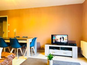un salon avec une table et une télévision dans l'établissement *Le Golden Blue* Magnifique T3 à 5min du centre avec parking gratuit, à Bellegarde-sur-Valserine