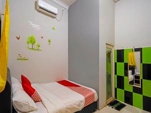 1 dormitorio con 1 cama y una pared verde y blanca en OYO 92451 Hasan House Syariah 2, en Nagoya