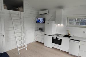 a kitchen with white appliances and a ladder in it at Attefallshus Nära Havet Norranäs in Varberg