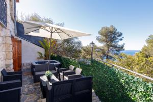 a patio with chairs and an umbrella and the ocean at Villa d exception avec terrasse, jacuzzi, vue mer, parking, en plein cœur du village de Eze in Èze