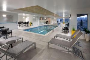 una piscina en un edificio con sillas y mesas en TownePlace Suites by Marriott Ellensburg, en Ellensburg
