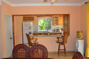 cocina con nevera blanca, mesa y sillas en 4 bedroom villa, security, private pool, ocean view, en Sosúa