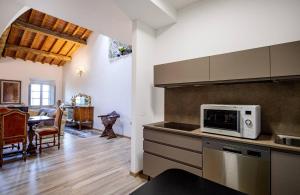 a kitchen with a microwave and a dining room at Il Loggiato di Lorena in Monteriggioni