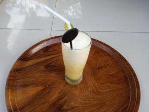 a drink on a wooden plate with a spoon at Buana Ubud Inn in Ubud