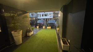 um corredor com um tapete verde num quarto com plantas em SaltStayz Golf Course Road em Gurgaon