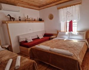 1 dormitorio con 2 camas y sofá rojo en Hotel Domino en Gjirokastër