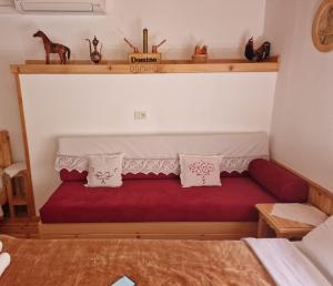 Un dormitorio con un sofá rojo con almohadas. en Hotel Domino en Gjirokastër