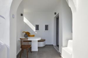 a white hallway with a table and a chair at Allure Breeze Suites in Oia