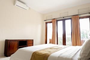 a bedroom with a bed and a large window at Puri Panca Jaya Hotel in Seminyak