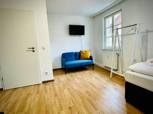 een slaapkamer met een blauwe stoel en een raam bij Apartment Goldschmied in Schwabach