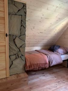 a bed in a room with a stone wall at Domek pod smrekami in Ropa
