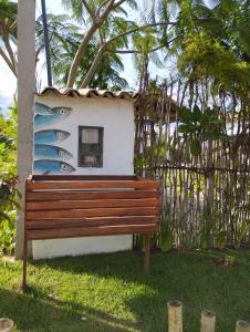 um banco em frente a um edifício com uma prancha de surf em Casa Tatuí em Pôrto de Pedras