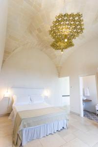 - une chambre avec un grand lit et un lustre dans l'établissement Dimora La Scaledda, à Serranova