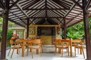 a wooden pavilion with wooden tables and chairs at Puri Panca Jaya Hotel in Seminyak