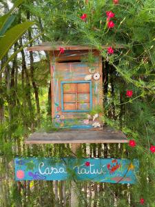 ein buntes Vogelhaus auf einem Baum mit Blumen in der Unterkunft Casa Tatuí in Pôrto de Pedras