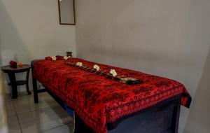 czerwone łóżko w pokoju ze stołem w obiekcie Puri Panca Jaya Hotel w mieście Seminyak