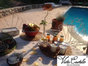 una mesa con comida y bebida junto a una piscina en Vista Castello, en Rovereto