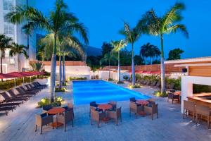 una imagen de una piscina del complejo con mesas y sillas en Marriott Port-au-Prince Hotel en Puerto Príncipe