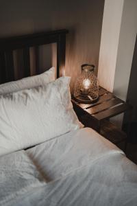 a bed with white sheets and a table with a lamp at No8 Boutique Hotel - self check in in Unterseen