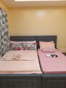 two beds in a room with pink and black bedskirts at Aussie Inn Baguio City Direct in Baguio