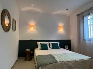 sypialnia z łóżkiem i 2 lampkami na ścianie w obiekcie Résidence Storia di Blue w mieście Porto-Vecchio