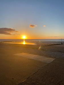 a sunset on a beach with the sun setting at Crispin House in Hunstanton