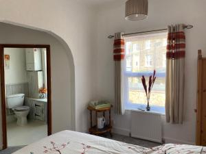 1 dormitorio con cama, ventana y aseo en Crispin House en Hunstanton