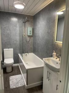 a bathroom with a tub and a toilet and a sink at River view Apartment in Glasgow