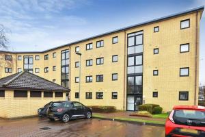 dois carros estacionados num parque de estacionamento em frente a um edifício em River view Apartment em Glasgow