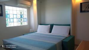 ein Schlafzimmer mit einem blauen Bett mit weißen Kissen und einem Fenster in der Unterkunft Monolocale mansarda a Porto Santo Stefano Argentario in Porto Santo Stefano