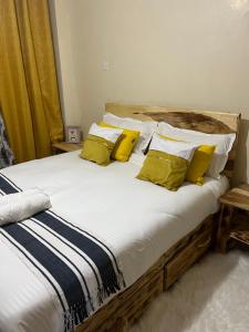 Una cama con almohadas amarillas y blancas. en Cozy 1br apartment in King’ong’o-Nyeri en Nyeri