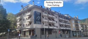 un gran edificio blanco con una señal de aparcamiento gratuita en Hotel Meson de L’Ainsa, en Aínsa