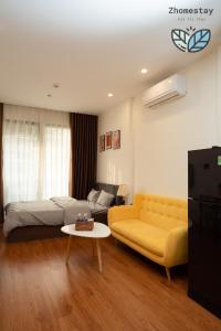 - un salon avec un canapé jaune et un lit dans l'établissement Vinhomes Smartcity-Căn hộ dich vụ -Zhomestay, à Phú Thú
