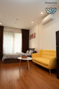 - un salon avec un canapé jaune et un lit dans l'établissement Vinhomes Smartcity-Căn hộ dich vụ -Zhomestay, à Phú Thú