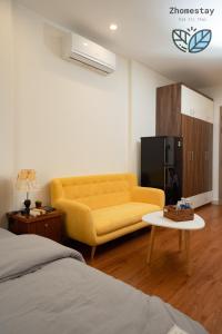 un salon avec un canapé jaune et une table basse dans l'établissement Vinhomes Smartcity-Căn hộ dich vụ -Zhomestay, à Phú Thú 6 autres photos