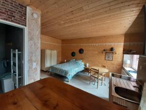 ein Schlafzimmer mit einem Bett und einem Tisch in einem Zimmer in der Unterkunft Studio dans bâtisse typique du Jura 