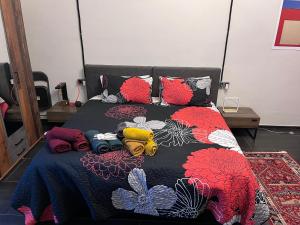 a bed with a black and red comforter and colorful pillows at Minardi Apartments in Vercelli