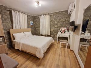 a bedroom with a bed and a desk and a television at The Stone House in Përmet