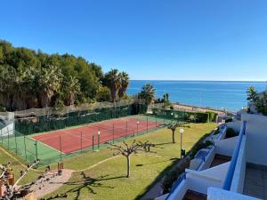 una pista de tenis con el océano en el fondo en Apartamentos Voramar Altamar, en Alcossebre