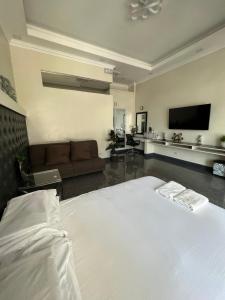 een slaapkamer met een wit bed en een bank bij Dampa Poolside Events & Accommodation 