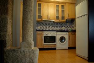 uma cozinha com armários de madeira e uma máquina de lavar louça branca em As Casiñas em Ribadavia