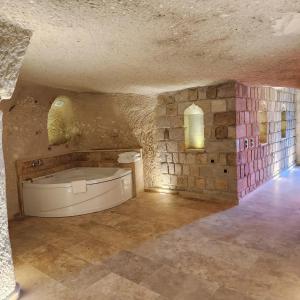 a large room with a bath tub in a stone wall at Elite Cave Suites in Göreme