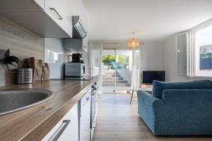 eine Küche mit einem Waschbecken und einem blauen Sofa in der Unterkunft Superbe T2 pour 4 pers dans Villa, coté Piscine in Cassis