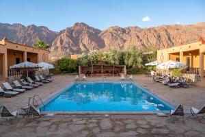 a swimming pool with chairs and mountains in the background at Auberge Kasbah Chez Amaliya in Tafraoute