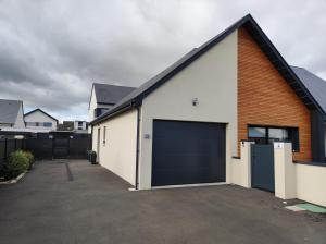 a garage with a building with a blue garage door at Studio les jardins de la brèche in Hermanville-sur-Mer